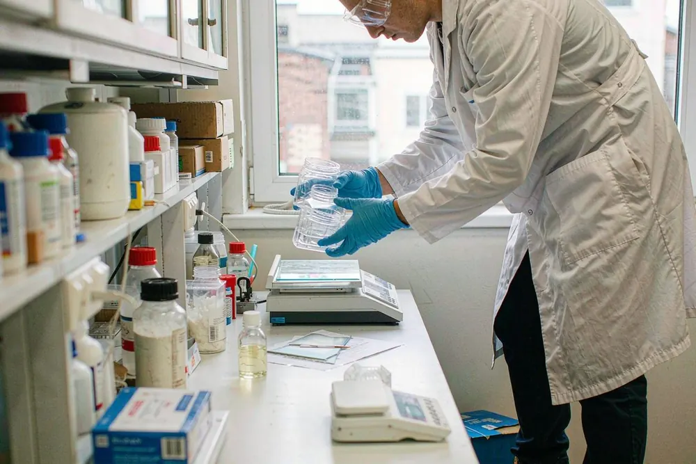 Lab technician in goggles and nitrile gloves with sample containers